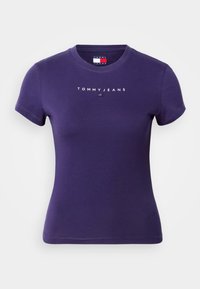 Violeta kokvilnas T-krekls ar apaļu kakla izgriezumu, īsām piedurknēm un "TOMMY JEANS" baltā krāsā izdrukāta uz krūtīm. Gluda tekstūra.