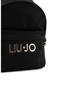 Zaino in nylon nero con parte superiore arrotondata, accento in logo argentato "LIU•JO" e dettaglio hardware laterale.