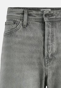 Grå denim jeans med en falmet overflade, der har en frontlukning med knap, bæltestropper og sidelommer. Tekstureret stof med synlige syninger.