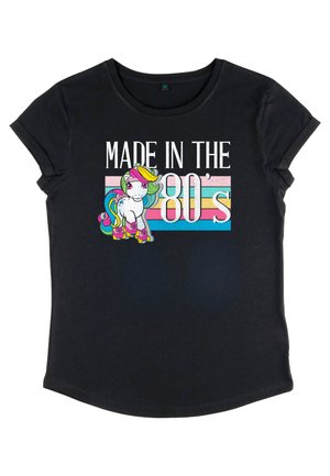 Sort bomulds t-shirt med et farverigt enhjørning grafik og teksten "MADE IN THE 80's", akkompagneret af en stribet pastelbaggrund.