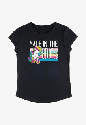 Sort bomulds t-shirt med et farverigt enhjørning grafik og teksten "MADE IN THE 80's", akkompagneret af en stribet pastelbaggrund.