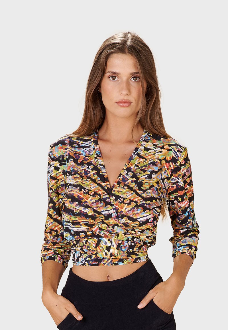 Långärmad croppad blus med ett livligt flerfärgat abstrakt mönster på en svart bakgrund, med en djup V-ringning och figursydd silhuett.