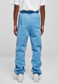 Blauwe, katoenen sweats met elastische tailleband en boorden. Beschikt over een achterzak en een relaxte pasvorm, gecombineerd met witte sneakers.