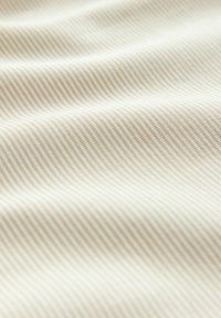 Tejido de color beige claro con finas rayas diagonales. La textura parece suave, con sutiles ondulaciones, mostrando un material suave y ligero.