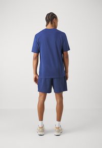 Ensemble composé d'un t-shirt en coton bleu marine et d'un short, offrant une coupe décontractée. Le matériau semble doux avec un design simple et un minimum de détails.