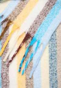 Sciarpa di lana multicolore con righe alternate in blu, giallo, marrone e crema. Presenta bordi frangiati e una finitura morbida e texturizzata.