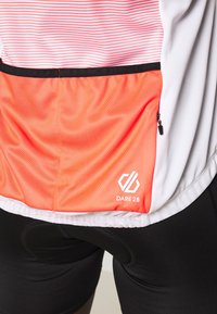 Męska koszulka do kolarstwa w kolorze białym z czerwonymi poziomymi paskami, z pomarańczową siateczkową kieszenią i czarnym zamkiem; widoczny logo.