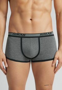 Grijze boxershorts van zachte stof, met een zwarte elastische tailleband met merknaam, en contrasterende zwarte afwerking langs de pijpen.