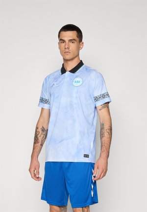 Maillot de sport bleu clair avec un col noir et des manches à motifs, arborant un logo circulaire. Porté avec un short bleu.