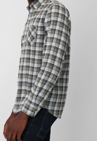 Langärmliges kariertes Hemd in Hellblau, Weiß, Marineblau und Braun. Mit Button-Down-Kragen, zwei Brusttaschen und geknöpften Manschetten. Aus Baumwollmischung.