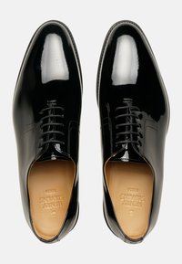 Schwarze, polierte Lederschuhe mit glatter Oberfläche, fünf Ösen und abgerundeter Spitze. Sie verfügen über eine hellbeige Lederinnensohle.