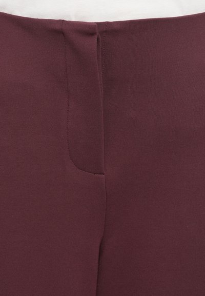 Burgundia püksid, millel on siledat tekstuuri ja õrn õmblusdetail taga. Omavad sobivat vööd ja ei sisalda nähtavat riistvara ega kaunistusi.