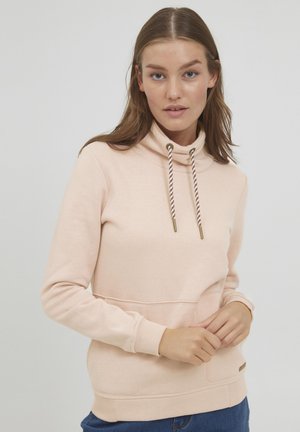 Lys rosa hettegenser laget av mykt stoff, med høy krage, snorer med gullakenter og en kengurulomme foran.