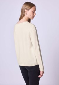 Hellbeige Pullover mit rundem Ausschnitt, langen Ärmeln und geripptem Saum. Weiche Textur und schlichtes Design. Die Ansicht zeigt die Rückseite.