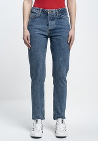 Blue denim jeans with a high waist, straight leg, and slight fading. Worn with white sneakers featuring black accents.