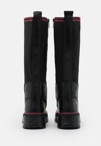 Bottes hautes noires avec une base en cuir lisse et une tige en tissu noir texturé. Elles comportent une bande accentuée rose et des fermetures éclair latérales pour un enfilage facile.
