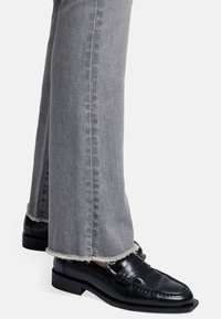 Grå denim flared jeans med slidte kanter og sorte læder loafers med hævet tå og subtile syninger.