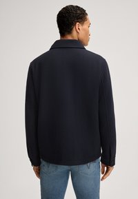 Veste en mélange de laine navy avec un grand col, des manches longues et des poignets boutonnés. Tissu lisse au toucher et coupe décontractée. Vue arrière montrée.