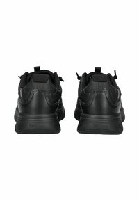 Pár černých sportovních tenisek, zobrazených z zadní strany, s texturovaným materiálem, úchyty a silnými podrážkami s názvem značky na patě.