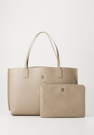 Beige läder tote-väska med två handtag, med subtila logotypdetaljer. Inkluderar en matchande dragkedjeväska, båda med en slät yta.