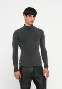 Tamno sivi dugi rukav turtleneck majica s rebrastom teksturom i prilagođenim krojem, s suptilnim šavovima duž šavova.
