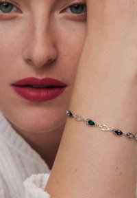 Srebrna bransoletka z owalnymi i marquise'owymi kamieniami w kolorach zielonym, niebieskim i pomarańczowym. Gładka faktura z połączonymi elementami metalowymi.