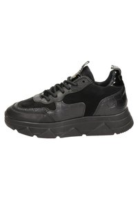 Zapatilla negra con un upper de cuero texturizado y ante, que cuenta con una suela gruesa y dentada y acentos brillantes en contraste. Detalles de los cordones y la etiqueta visibles.