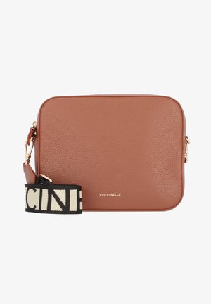 Sac bandoulière rectangulaire en cuir marron avec une sangle réglable noire et blanche et des ferrures dorées, nom de la marque "Coccinelle" à l'avant.