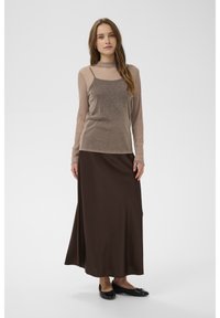 Ruda ilga sijonas su aptemptu, blizgančiu ilgomis rankovėmis ir aukštu kaklu megztuku. Modelis vilki juodus lygios nosies batelius. Lygus tekstūra ir sluoksniuota konstrukcija.