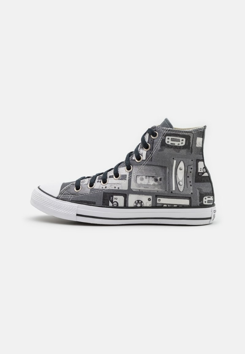 Baskets montantes avec motif de bande cassette noir et blanc, semelle en caoutchouc blanche et lacets noirs sur fond blanc uni.