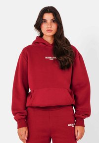 Bordeaux hoodie met een voorzak, geribbelde manchetten en een trekkoord capuchon. Voorzien van witte tekst met "SIXTH JUNE PARIS" op de borst.