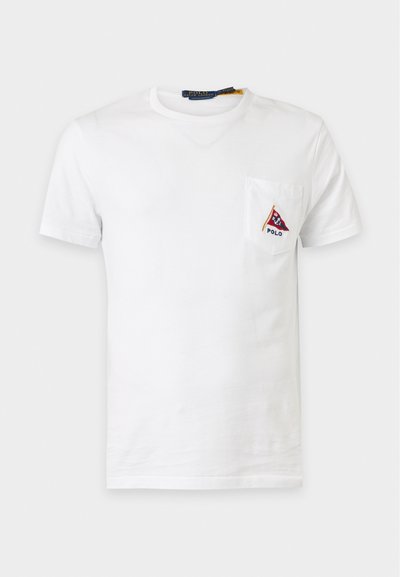 Λευκό κοντομάνικο T-shirt με τσέπη στο αριστερό στήθος που έχει κόκκινο και μπλε τριγωνικό λογότυπο Polo και κείμενο από κάτω.