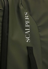 Mochila verde oscura con tejido texturizado, acentos negros y el logo blanco "SCALPERS". Incluye una asa trenzada en el lateral.