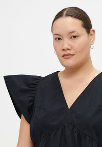 Black dress with a deep V-neck, short flutter sleeves, and gathered fabric at the waist. Smooth texture, lightweight material.