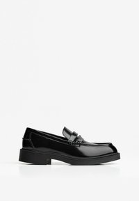 Loafers din piele lacuită neagră, cu vârf rotund, talpă plată și un bandou decorativ în partea din față. Design minimalist cu textură netedă.