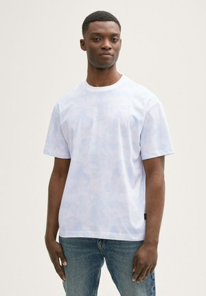 Lysblå kortærmet t-shirt med et subtilt camouflage-mønster, rund hals og afslappet pasform. Parret med blå denimjeans.