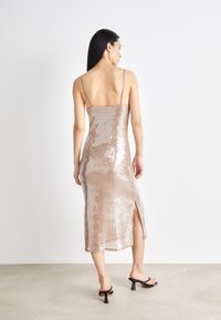 Μάξι φόρεμα με παγιέτες σε μπεζ απόχρωση, με λεπτές τιράντες; στενή σιλουέτα; πλάγιο άνοιγμα; υφή επιφάνειας; λείο ύφασμα με ανακλαστικές λεπτομέρειες.