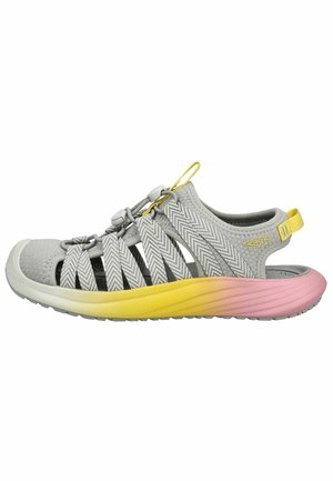 Graue Sandale mit geschlossenem Zehenbereich, Chevron-geformten Riemen und einer Sohle mit Farbverlauf von Gelb zu Pink, ausgestattet mit einem verstellbaren Knebelverschluss und Zuglaschen.