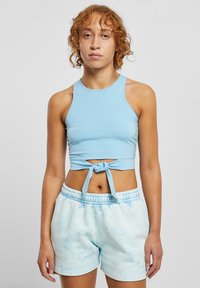 Crop top bleu deschis cu un design fără mâneci �și un nod în față, asortat cu pantaloni scurți bleu deschis cu tie-dye și talie elastică.