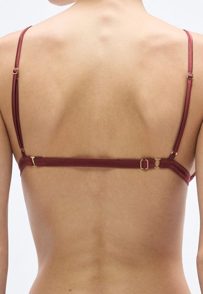 Sutien roșu din satin, cu bretele subțiri și detalii aurii din metal. Partea din spate are închidere cu cârlig și ochi. Textură netedă, design minimalist.