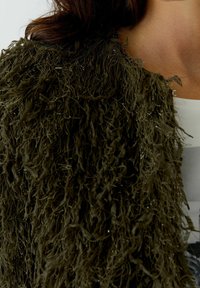 Faux fur jacket in olive green with a shaggy texture, featuring metallic thread accents and an open front design.