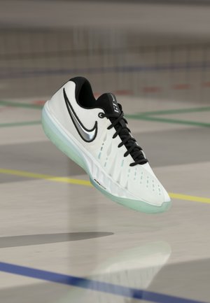 Zapatilla deportiva blanca con detalles en negro, parte superior de malla, suela texturizada y logo reflectante de Nike. Cordones visibles y detalles de diseño perforados.