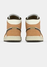 Magas szárú sportcipők párja, bézs velúrból és krémszínű bőrből, hátulról nézve, egyszerű fehér háttér előtt.