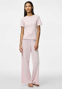 Jasnoróżowy zestaw piżamowy z prążkowaną fakturą, falbaniastymi brzegami, krótkimi rękawami i spodniami o szerokich nogawkach z pionowymi paskami.