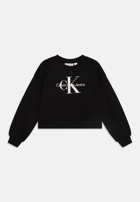 Svart cropped hettegenser laget av bomull, med et stort sølvfarget "CK"-logo og hvit "Calvin Klein Jeans"-tekst foran. Ribbestrikkede mansjetter og nederkant.