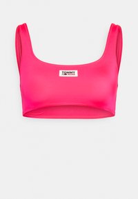 Rózsaszín, rövidített tank top sima anyagból, széles pántokkal és négyzet alakú nyakkivágással. Az elülső részen egy kis téglalap alakú logótábla látható.