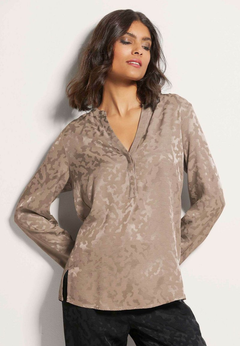 Langärmlige Bluse in Taupe mit einem subtilen abstrakten Muster, ohne Knopfleiste und mit seitlichen Schlitzern, aus glattem, leichtem Stoff gefertigt.