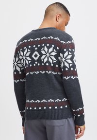Donkergrijze gebreide trui met witte en rode sneeuwvlokpatronen, geribde mouwen en zoom, en een klassiek ronde halsontwerp.