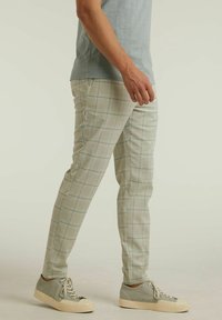 Ljust gröna rutiga byxor med slim fit, som har subtila blå linjer. Matcher med ljusgrå sneakers som visar en texturerad tyg.