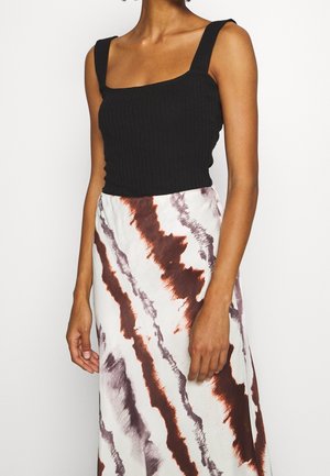 Black ribbed tank top with square neckline paired with a long skirt featuring a white and red abstract pattern. Textured fabric with a fitted silhouette.
